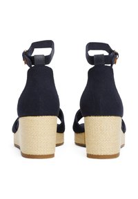 Sandali con zeppa in tela blu navy, caratterizzati da una piattaforma in paglia texturizzata e una cinghia alla caviglia con dettaglio in metallo dorato.