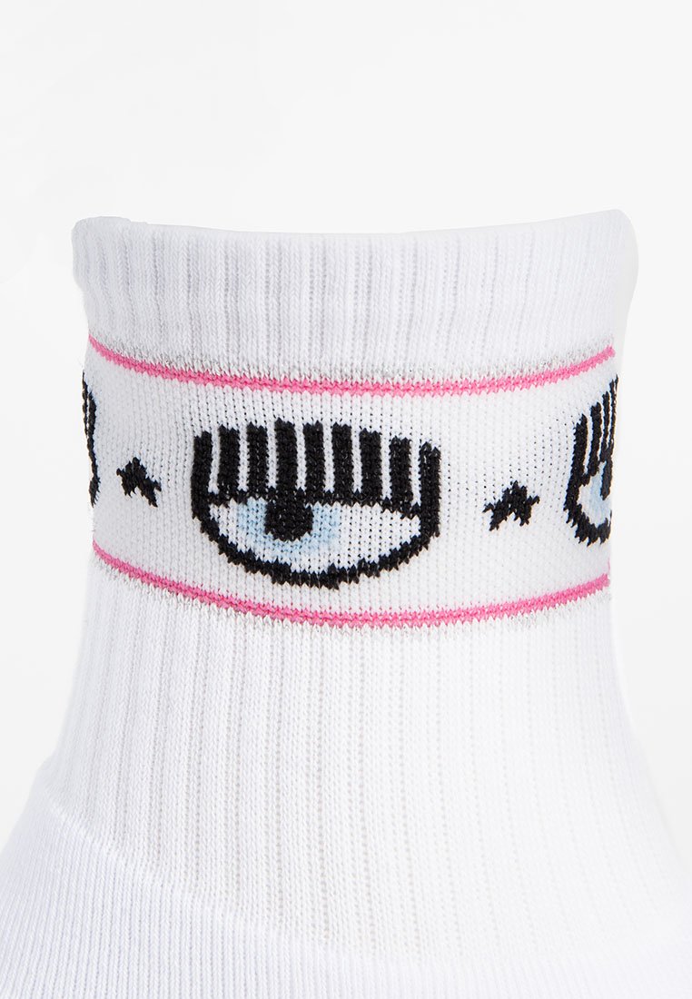 Calzini bianchi a crew con una texture a coste. Il bordo presenta occhi in stile cartone animato e accenti rosa, con dettagli neri e blu.