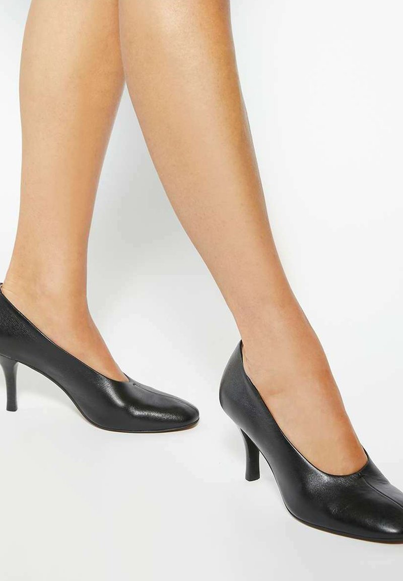 Black leather high-heeled shoes with a pointed toe and cut-out sides, featuring a moderate heel height and smooth texture.