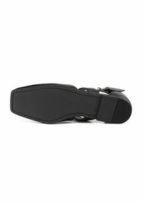 Sandale en cuir noir vue par la semelle, montrant une semelle plate et lisse avec un petit talon empilé et une bride à boucle.