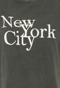 Dark gray t-shirt featuring bold white text spelling "New York City," with varying font sizes and styles for visual interest.