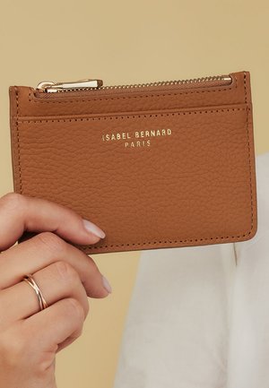Tan leather cardholder with a textured finish, featuring a zippered pocket and embossed gold logo "ISABEL BERNARD PARIS."