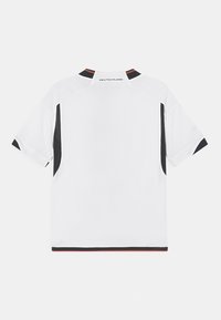 Camiseta blanca de manga corta con detalles en negro, cuello redondo y texto "DEUTSCHLAND" en la espalda. Hecha de tela ligera y texturizada.