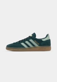 Baskets en suede vert avec trois rayures vert clair, semelle en caoutchouc gomme et texte doré "Spezial" sur le côté. Design low-top avec bout arrondi.