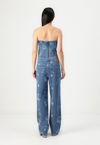 Jeans topp uten stropper i denim med glidelås bak, parret med brede benbukser med et lett kirsebærmønster, alt i mellomblå vask.