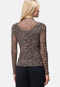 Gennemsigtig langærmet bluse i leopardprintdesign med varierende brune og sorte nuancer, der har en scallop-udskæring ved halsen og en tætsiddende silhuet.