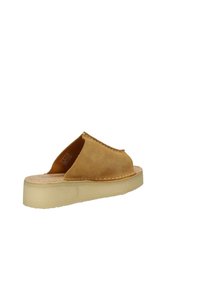 Sandalo scivolato in suede marrone chiaro con punta arrotondata, dettagli cuciti e suola in gomma di un colore chiaro. Design minimalista e texture liscia.