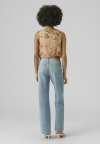 Top senza maniche leggero di colore rosa con stampa floreale abbinato a jeans dritti a vita alta di colore azzurro chiaro. Design minimalista con dettagli sottili sul retro.