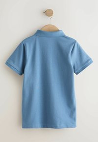 Lyseblå kortærmet polo-shirt hængende på en træbøjle. Har en flad krave, blød tekstur og pæn afslutning langs kant og ærmer.