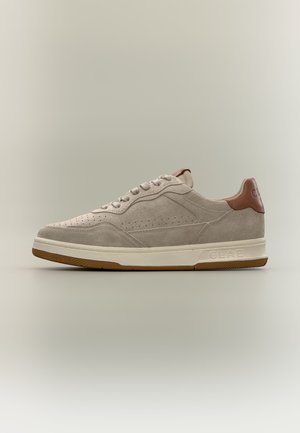 Baskets basses en daim beige avec perforations, semelle blanche, languette de talon marron et marquage en relief "CLAE" sur le côté de la semelle.