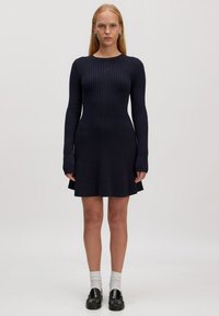 Dunkelblaues geripptes Strickkleid mit langen Ärmeln, tailliertem Oberteil, schwingendem Rock und rundem Ausschnitt; verfügt über ein strukturiertes Muster und einen weichen Stoff.