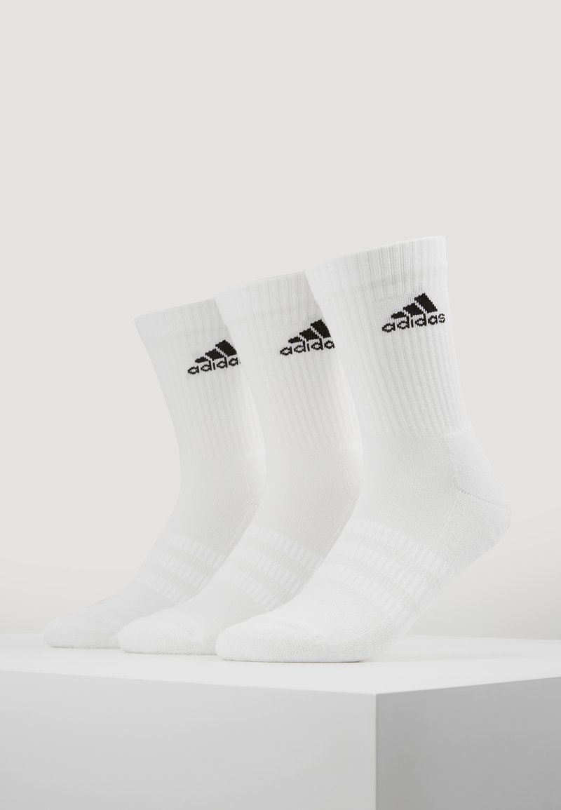 Valged sportlikud sokid ribakujulise tekstuuriga, millel on must Adidas'i logo ja kolm triibulikku aksenti varre peal. Kuvatud on kolm paari.