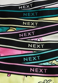 Sous-vêtements colorés avec des ceintures élastiques noires portant le mot "NEXT" dans différentes couleurs, agrémentés de graphismes ludiques.