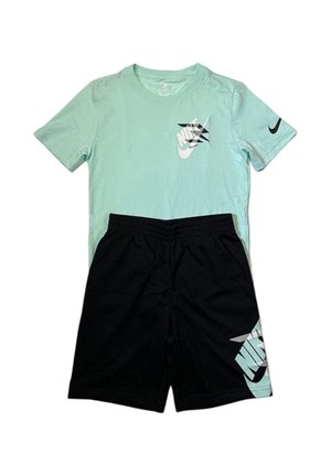 T-shirt Nike azzurro chiaro con logo swoosh nero e pantaloncini neri con grande logo Nike azzurro chiaro sulla gamba.
