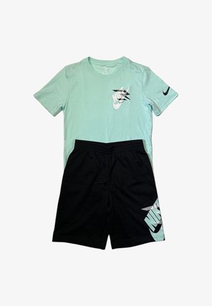 T-shirt Nike azzurro chiaro con logo swoosh nero e pantaloncini neri con grande logo Nike azzurro chiaro sulla gamba.
