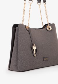Borsa grigia effetto testurizzato con due tracolle in catena dorata e hardware circolare. Presenta un charm a forma di chiave e un piccolo logo sul fronte.