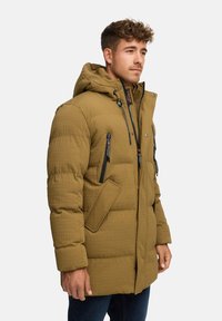 Khaki pufferjack met capuchon, met een gestructureerde afwerking, meerdere rits- en steekzakken, en decoratieve hardewaren accenten.
