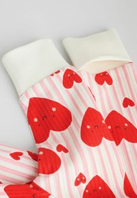 Calze al ginocchio con trama a coste, caratterizzate da cuori rossi e strisce rosa, sormontate da un risvolto bianco.