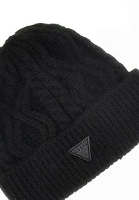 Czarna dzianinowa czapka z teksturowanym wzorem w warkocz, z prążkowanym mankietem i trójkątną gumową łatą z logo z przodu.
