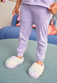 Leggings lilas con patrones de helados, nubes, flores y arcoíris; combinados con pantuflas esponjosas y en colores pastel. Tejido suave y elástico.
