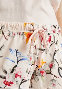 Floral shorts with a drawstring waist in a soft fabric. Features pink, yellow, and blue floral patterns against a light background.