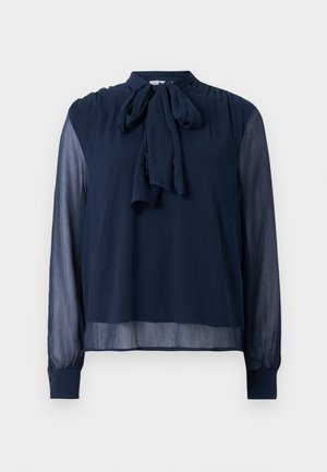 Blouse long à manches transparentes bleu marine avec un nœud à l'encolure et des poignets boutonnés, présentant un tissu légèrement texturé.