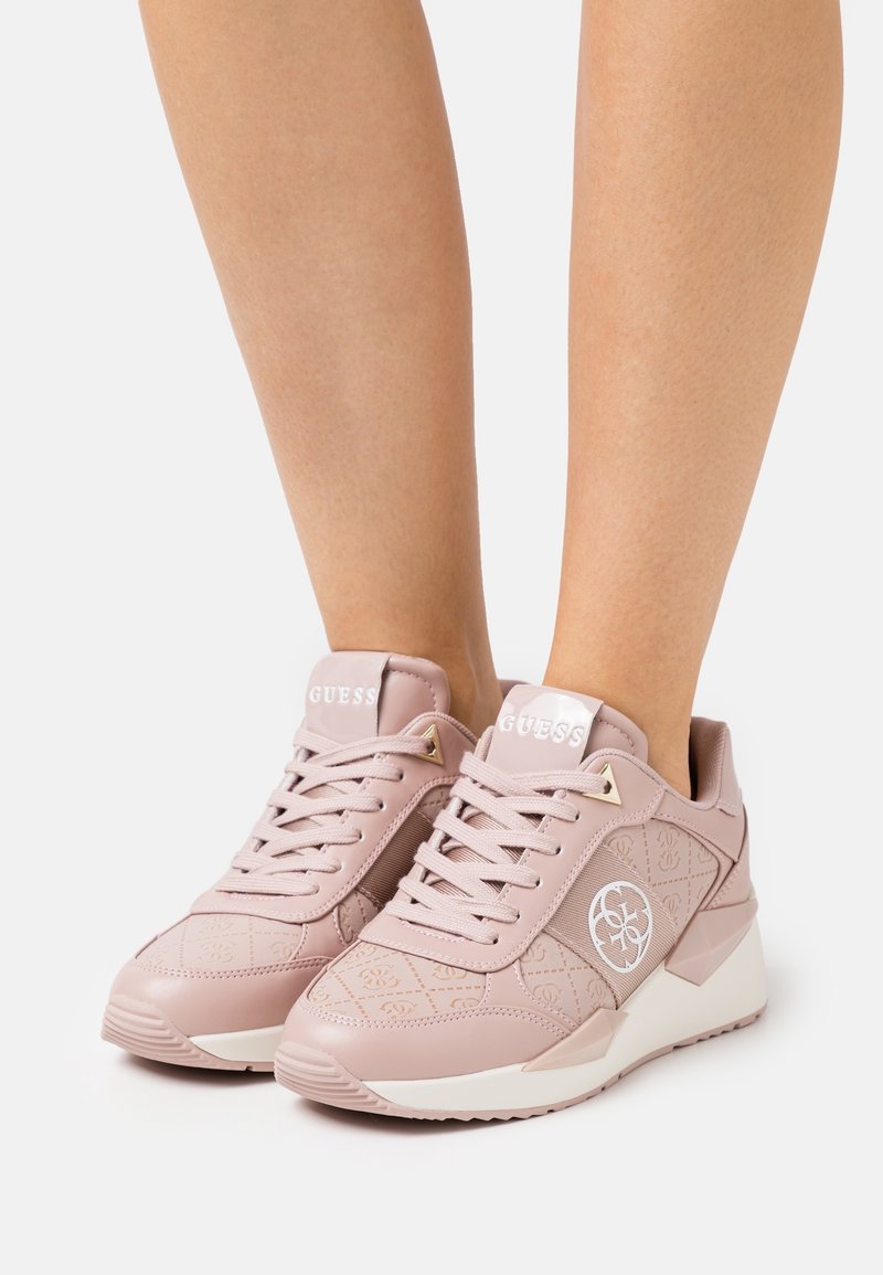 Des baskets rose clair avec un design texturé, des lacets et des accents blancs. Elles présentent un logo sur le côté et une semelle rembourrée.