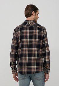 Camicia a quadri con tonalità di nero, beige e grigio, dotata di colletto con bottoni e maniche lunghe. Realizzata in un tessuto testurizzato.