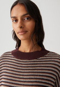 Knitted sweater with a wide, ribbed maroon collar, featuring a striped pattern in brown, white, and black tones. Soft texture and relaxed fit.