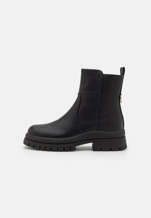 Bottines noires en cuir lisse, avec une semelle épaisse, un panneau élastique sur le côté et une languette à l'arrière pour un enfilage facile.