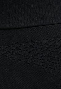Tessuto a maglia nera con un motivo testurizzato caratterizzato da linee in rilievo e una vita liscia. Materiale morbido e elasticizzato adatto per l'abbigliamento sportivo.