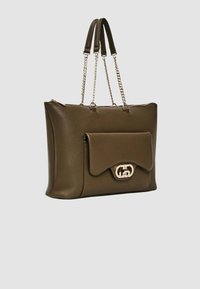 Borsa tote in pelle verde oliva con doppi manici, dettagli in catena e patta frontale con chiusura metallica. Texture liscia. Chiusura con zip.