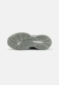 Semelle de chaussure en matériau en caoutchouc translucide, avec un motif de semelle élaboré et un mélange de formes courbes et angulaires pour l'adhérence et le soutien.