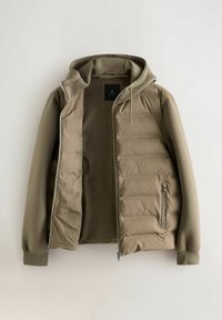 Khaki kurtka z miękką, teksturowaną zewnętrzną częścią, wypełnionym korpusem i przypinaną kapturem. Posiada zamek błyskawiczny z przodu oraz kieszenie boczne.