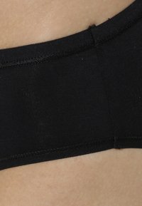 Schwarzer nahtloser Bund aus dehnbarem, weichem Stoff; zeichnet sich durch eine glatte Textur ohne sichtbare Muster oder Beschläge aus.