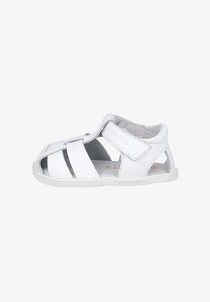 Sandalia para bebé de cuero blanco con diseño de puntera cerrada, correa ajustable de velcro y aberturas laterales transpirables en una suela de goma plana.