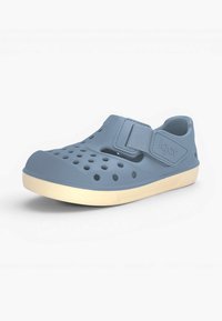 Chaussure bleue à enfiler avec des trous de ventilation, bride réglable avec logo "igor", et semelle de couleur claire, présentée sur fond blanc.