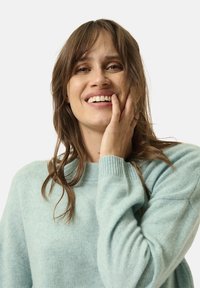 Hellblauer, weicher Pullover aus einem flauschigen Material, mit einem einfachen runden Ausschnitt und gerippten Bündchen. Lockere Passform mit leicht übergroßem Design.