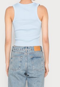 Ljusblå ribbad linne skjorta i kombination med högmidjade denimjeans. Jeansarna har en urblekt textur och synlig sömnad, med ett lädermärke.