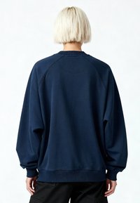 Sweatshirt oversize bleu marine avec manches raglan, poignets et ourlet côtelés, présentant une texture lisse. Vue de dos montrant un design simple.