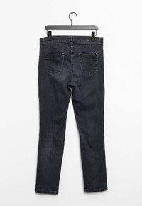 Dark wash denim jeans with a slim fit, featuring five pockets, back yoke, and stitched detailing. Hangs from a black plastic hanger.