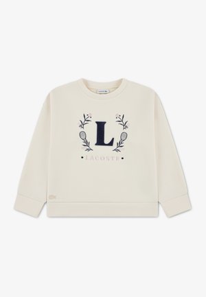 Krém színű pulóver sötétkék "L" logóval és virágmintákkal, bordázott mandzsettákkal és szegéllyel. Fehér háttéren vízszintesen elhelyezve.