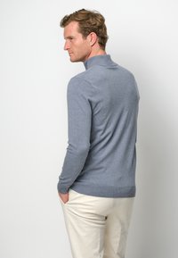 Grauer Strickpullover mit hohem Kragen, gerippten Bündchen und Saum. Verfügt über ein figurbetontes Design, glatte Textur und minimalistischen Stil.