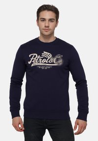 Felpa blu navy con maniche lunghe. Presenta una grande grafica color crema con la scritta "Petrol&C" sul davanti. Realizzata in un morbido tessuto testurizzato.