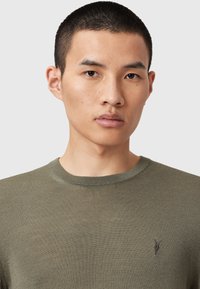 Olivengroen ribbel T-shirt met een ronde halslijn, korte mouwen en een subtiele geborduurde acccent op de borst. Katoenmengsel.