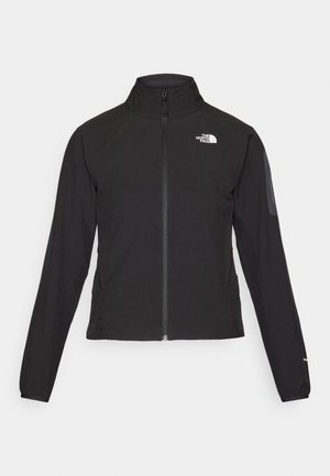 Svart zip-up jakke med høy krage, teksturert stoff, og logo på venstre bryst. Har lange ermer og en tettsittende design.