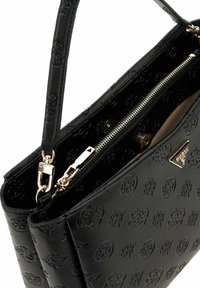 Sac à main en cuir noir avec des motifs en relief, matériel en métal doré, fermeture éclair et une seule bandoulière. Compartiments intérieurs visibles.