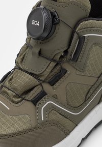 Zielone buty sportowe z systemem sznurowania Boa, teksturowana cholewka, materiał syntetyczny, białe akcenty i podeszwa z gumy.