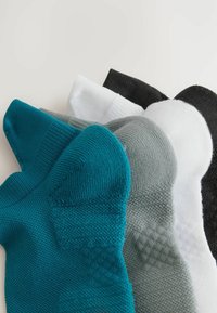 Balenie štyroch ponožiek v odtieňoch teal, šedej, bielej a čiernej. Mäkko tkané s textúrou a zosilnenou oblasťou päty a špičky. Každá ponožka má odlišnú farbu.