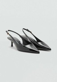 Talons slingbacks en cuir verni noir avec des bouts pointus, présentant un talon fin et un subtil accent doré sur la sangle. Texture lisse.